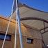 The PTFE canopy is stretched in place by rigid tubular trusses stemming between the central spine truss and the steel tripods at the perimeter as seen here