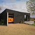 This image: The bold black block and monochrome decking enhance the surrounding landscape