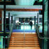 The aesthetic is a modified High-Tech, where natural wood and stone balance slender steel columns