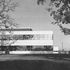The marketing building seen across its lawn with beautiful mature trees. The doors in the façade give access from the canteen to the outside eating area