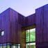 The cedar cladding runs vertically from the top of the first floor windows and horizontally below