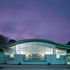 The curved roof profile and the glazed wall give the building a dramatic look at night