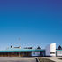 From the north the building is long, low and elegant.  The entrance is signalled by a white-rendered,  curved form with a horizontal slit window.  A patinated copper roof hoods the undulating timber-glazed screen 