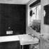 The bathroom has white enamel and chocolate walls with a light red linoleum floor
