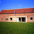 The new north wall of Hall Barn is made of straw bales, faced with a rainscreen of translucent glass fibre panels fixed to steel frames which span between the original oak posts