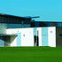 The massively overhanging butterfly roof is tied down by a colonnade of inclinded circular steel columns