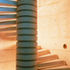 Fair-faced concrete spiral stair, exposed spine and treads held away from the wall to allow light to filter down
