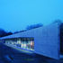 The west facade; 160m long working wall is predominantly natural grey concrete, with areas of glazing