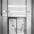 Glazed screen at the entrance to the main consular office space. Through the door may be seen standard office partitioning faced in white plastic and the continuous suspended ceiling