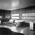 View showing the opposite wall with its cupboards fitted with maple tambour doors. The edges and interiors of the cupboards are painted pale blue. The wall panelling is of French walnut. The fireplace at the far end is set in a frame of Levanto marble