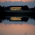 The building lit up at sunset, reflecting in the surrounding lake