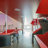 Red-painted steel stairs and walkways to the theatre and studio theatre above are suspended like theatre scenery in the glazed gap between the old and new buildings