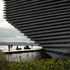 The building is striated with horizontal lines of gapped, trapezoidally sectioned concrete ribs