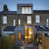 A large glazed pivot door creates a dramatic connection to the rear garden